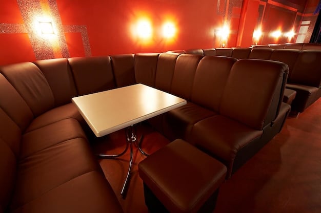 A luxurious movie theater interior featuring reclining leather seats, individual tables with food and drinks, and a large, curved screen displaying a blockbuster film. The image showcases the enhanced comfort and amenities that theaters are now offering to attract moviegoers.