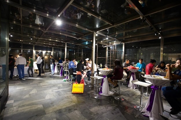 A multi-purpose venue hosting a daytime event such as a food festival or an art exhibition, with live music playing in the background. The space is filled with people of all ages and backgrounds.