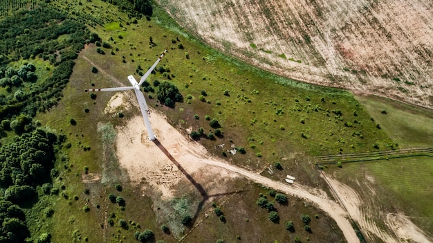 An aerial view of a large-scale wind farm project under construction, featuring wind turbines being assembled and installed on a vast open field. Construction vehicles and equipment are visible around the turbines.