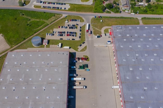 An aerial view of a large distribution center with trucks loading and unloading goods. There are numerous shipping containers and packages visible, suggesting a high level of activity and efficient supply chain operations. The sky is slightly overcast.