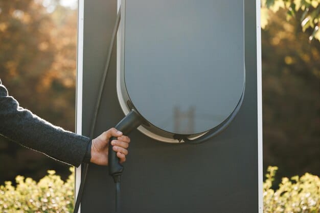 A close-up of an electric vehicle charging station with a hand plugging in the charger, emphasizing the transition to electric transportation.